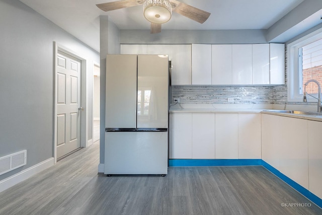 kitchen with wood finished floors, visible vents, freestanding refrigerator, a sink, and modern cabinets