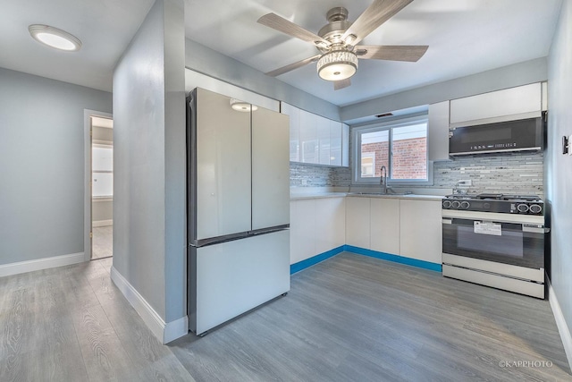 kitchen with gas range, modern cabinets, white cabinets, and freestanding refrigerator