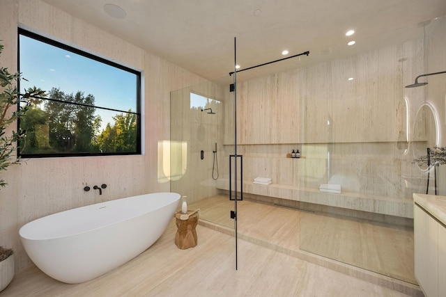 bathroom with a stall shower, recessed lighting, a freestanding tub, and vanity