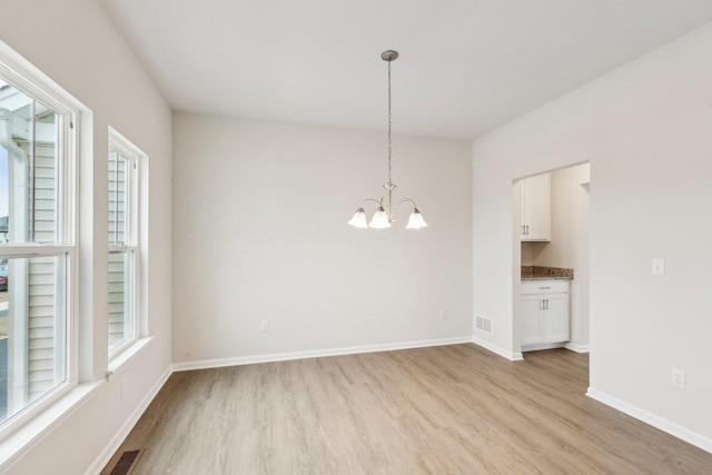 unfurnished room with light wood-style flooring, plenty of natural light, visible vents, and baseboards