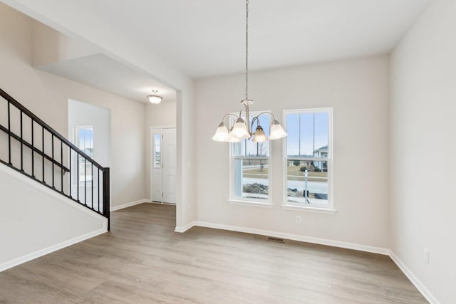 unfurnished dining area with stairs, baseboards, wood finished floors, and a healthy amount of sunlight