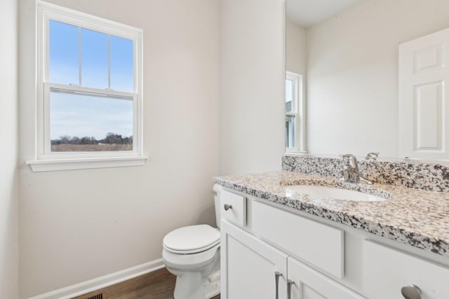 half bathroom featuring toilet, baseboards, wood finished floors, and vanity