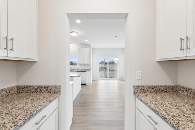 kitchen with light wood-style floors, recessed lighting, white cabinets, and light stone counters