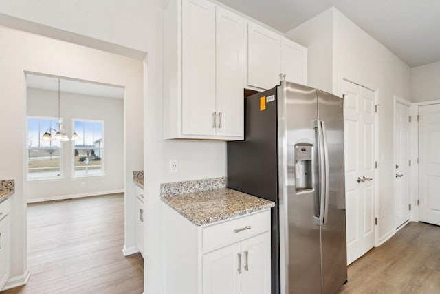 kitchen featuring baseboards, white cabinets, light wood-style floors, stainless steel refrigerator with ice dispenser, and light stone countertops