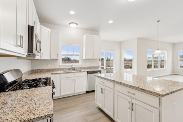 kitchen with a kitchen island, a sink, light wood-style floors, white cabinets, and appliances with stainless steel finishes