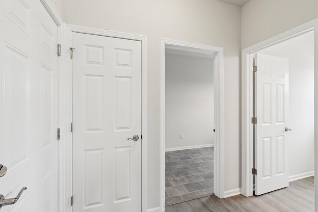 hall with light wood-type flooring and baseboards