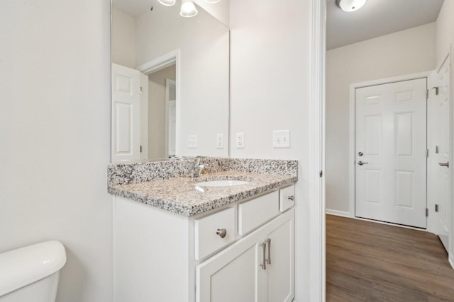 half bath featuring vanity, toilet, and wood finished floors