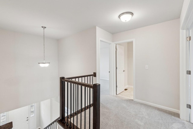 hall featuring baseboards, carpet flooring, and an upstairs landing