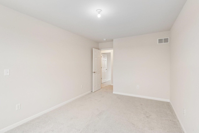 empty room with light colored carpet, visible vents, and baseboards