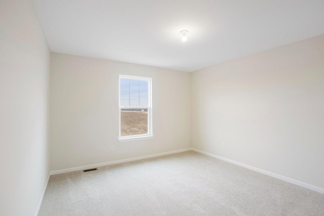 carpeted empty room featuring baseboards and visible vents