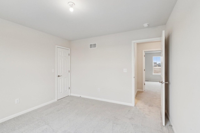 unfurnished room featuring baseboards, visible vents, and light colored carpet