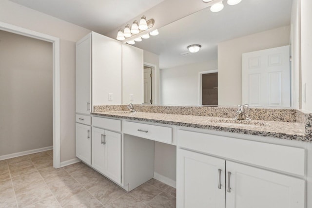 full bath featuring double vanity, a sink, and baseboards