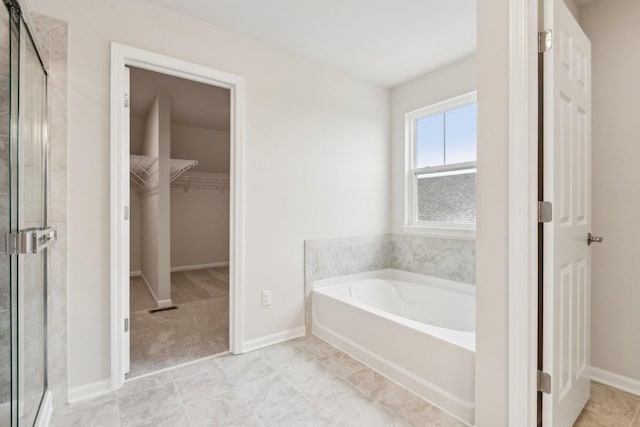 full bath with a garden tub, a spacious closet, a shower stall, and baseboards