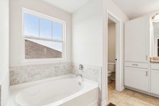 full bathroom featuring tile patterned floors, toilet, and a bath