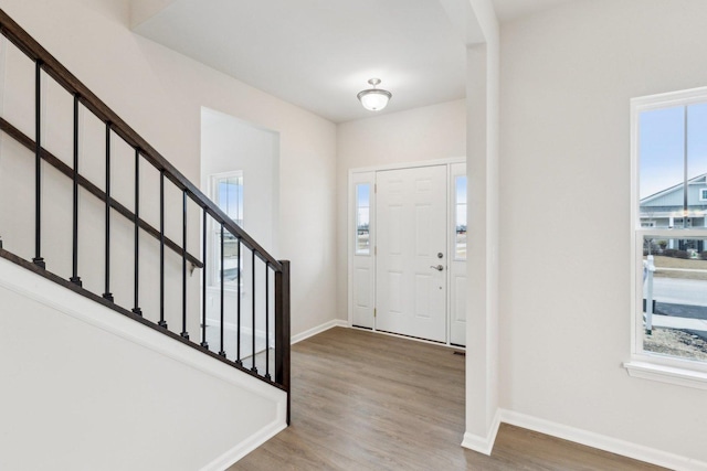 entrance foyer featuring stairs, a wealth of natural light, baseboards, and wood finished floors