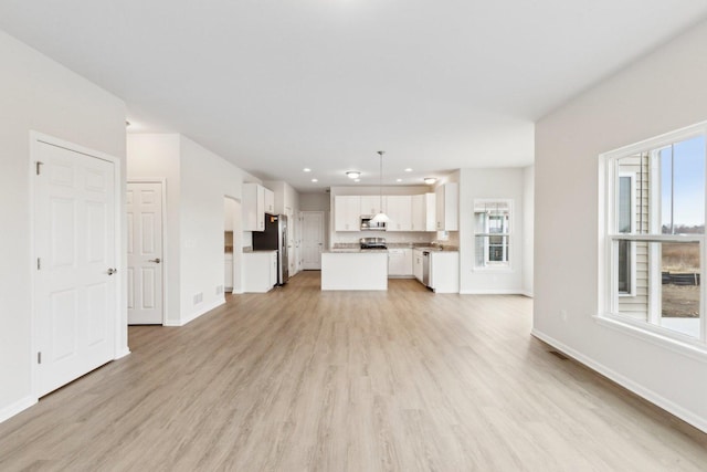 unfurnished living room with recessed lighting, light wood-style flooring, and baseboards