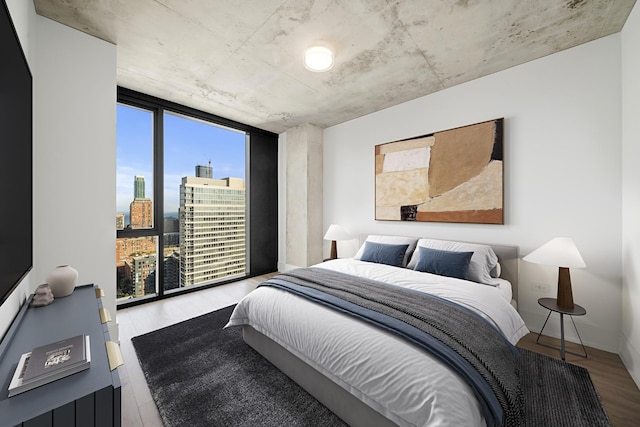 bedroom featuring floor to ceiling windows, a city view, and wood finished floors