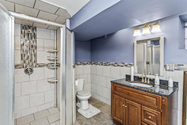 full bath with a stall shower, toilet, tile patterned flooring, vanity, and tile walls