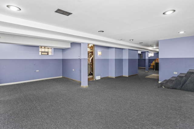 basement featuring dark colored carpet, visible vents, and baseboards