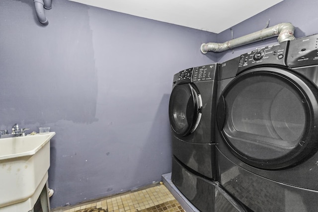 clothes washing area with laundry area, a sink, and washer and clothes dryer