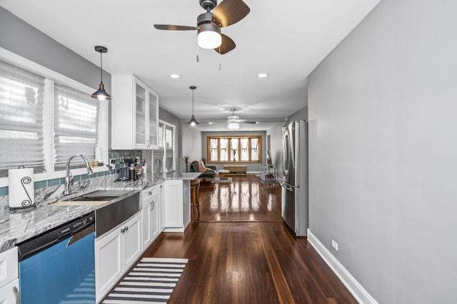 kitchen featuring white cabinets, dishwasher, glass insert cabinets, freestanding refrigerator, and light stone countertops