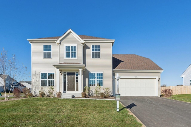 view of front facade featuring a front yard, driveway, an attached garage, and fence