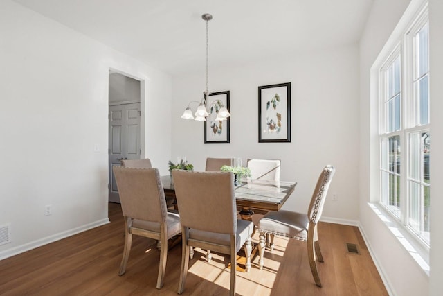 dining space featuring a chandelier, visible vents, baseboards, and wood finished floors