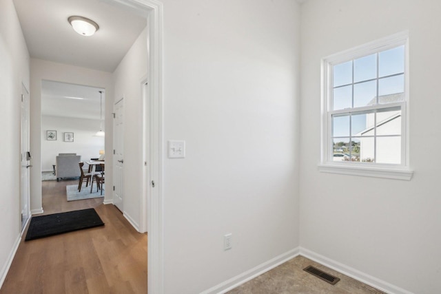 corridor featuring baseboards, visible vents, and wood finished floors