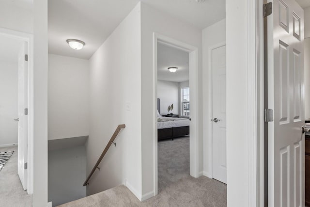 hall featuring baseboards, carpet flooring, and an upstairs landing