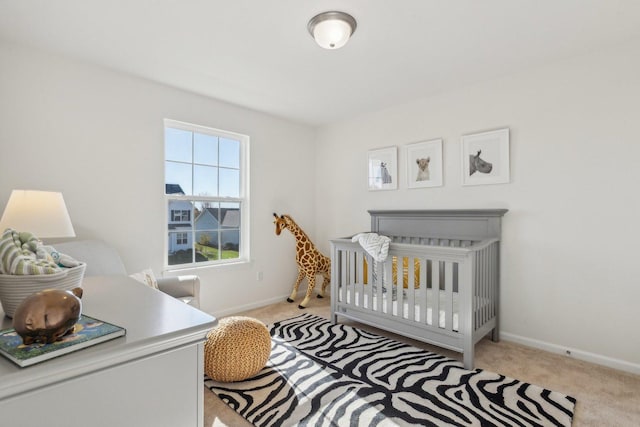 bedroom featuring carpet flooring, a crib, and baseboards