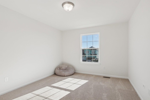 empty room with carpet floors, visible vents, and baseboards