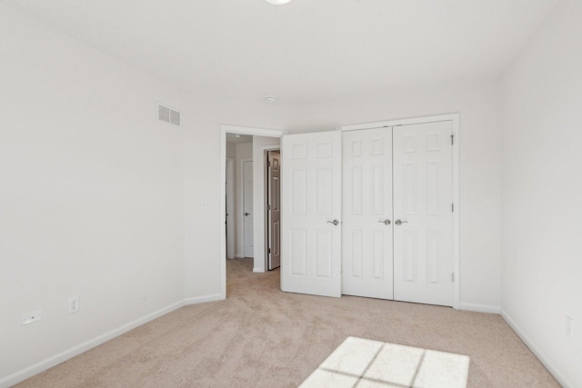 unfurnished bedroom with baseboards, a closet, visible vents, and carpet flooring