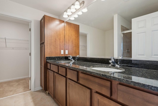 bathroom with double vanity, tile patterned flooring, a sink, and a shower stall