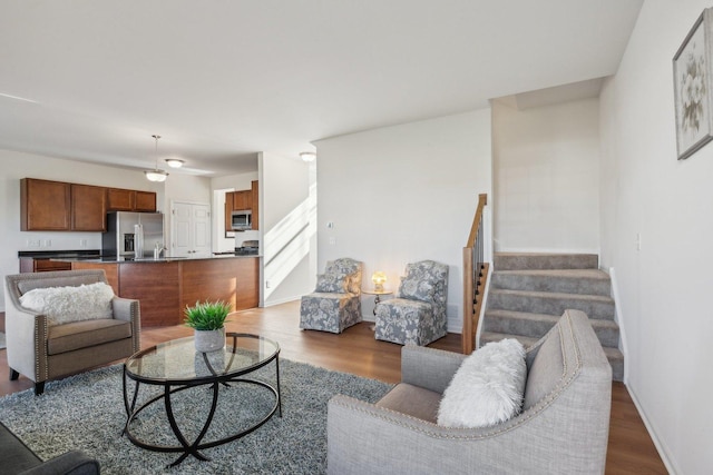 living area with stairs, baseboards, and wood finished floors