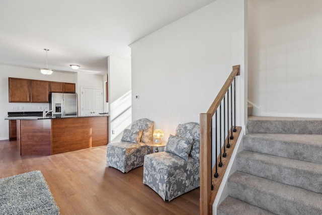 kitchen featuring open floor plan, wood finished floors, and stainless steel fridge with ice dispenser