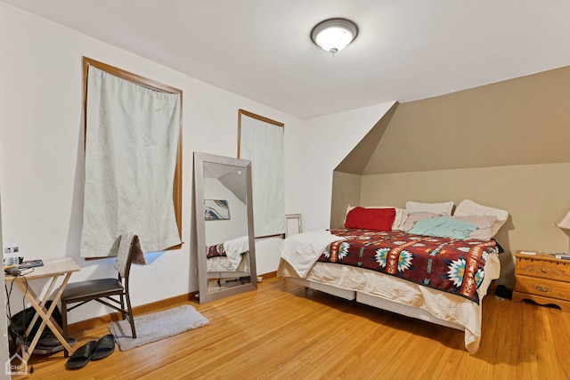 bedroom featuring lofted ceiling, light wood-style flooring, and baseboards