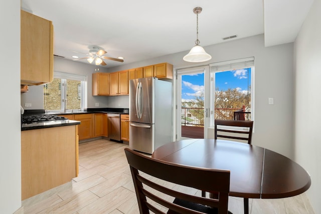 kitchen featuring dark countertops, visible vents, ceiling fan, hanging light fixtures, and stainless steel appliances