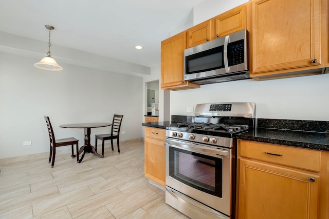 kitchen featuring dark stone counters, decorative light fixtures, recessed lighting, and appliances with stainless steel finishes