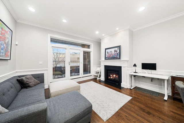 living area featuring crown molding, recessed lighting, a fireplace with flush hearth, wainscoting, and wood finished floors