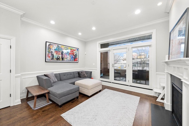 living area featuring a decorative wall, a fireplace with flush hearth, dark wood finished floors, and crown molding