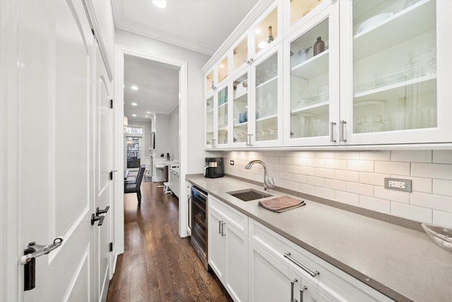 kitchen featuring wine cooler, backsplash, ornamental molding, white cabinets, and a sink