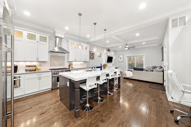 kitchen with a breakfast bar, visible vents, open floor plan, high end range, and wall chimney exhaust hood