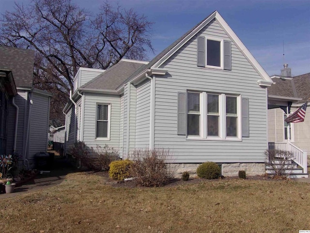 view of property exterior with a shingled roof and a yard