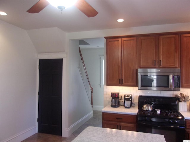 kitchen with black range with gas cooktop, stainless steel microwave, tasteful backsplash, and light countertops