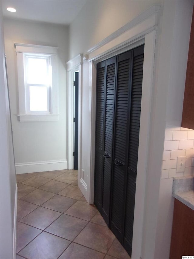 hallway featuring light tile patterned floors and baseboards