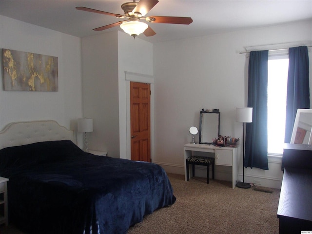 carpeted bedroom with ceiling fan and baseboards