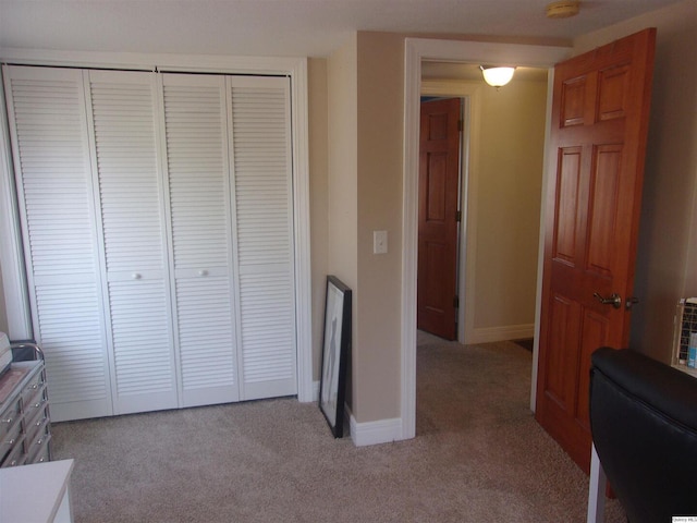 bedroom featuring a closet, light carpet, and baseboards