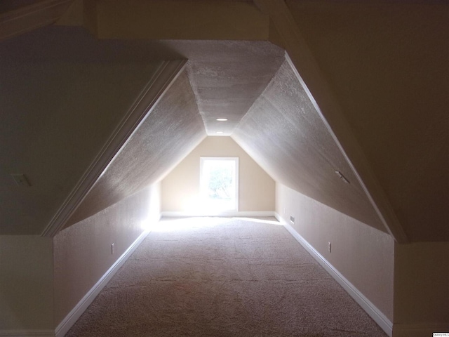 additional living space with carpet floors, lofted ceiling, a textured ceiling, and baseboards