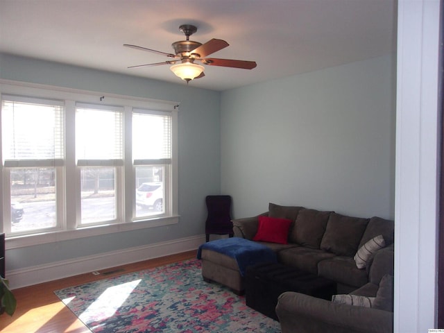 living room with a ceiling fan, baseboards, and wood finished floors