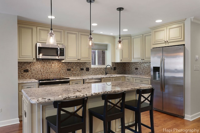 kitchen with stainless steel appliances, cream cabinets, light wood-style flooring, and decorative backsplash